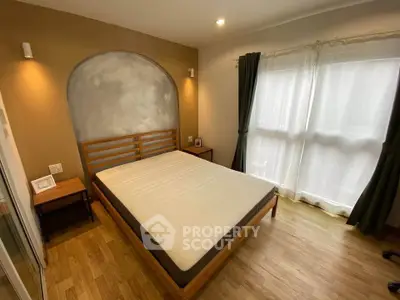 Cozy bedroom with wooden flooring and natural light through large windows.