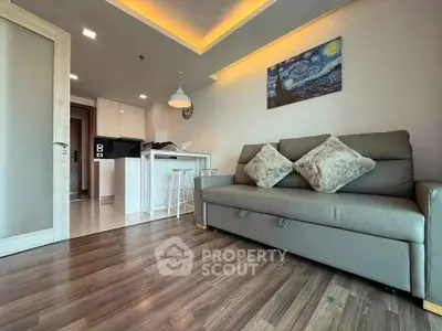 Modern living room with stylish decor and open kitchen layout, featuring cozy sofa and elegant lighting.