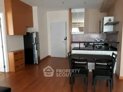 Modern kitchen with dining area featuring sleek appliances and wooden flooring.