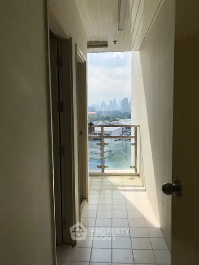 Bright hallway leading to a balcony with stunning city skyline view, perfect for urban living.