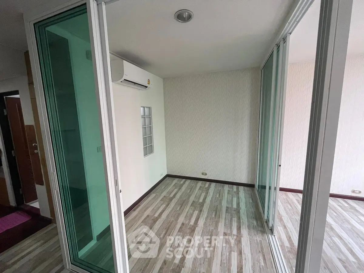 Spacious room with wooden flooring and glass sliding doors in modern apartment.