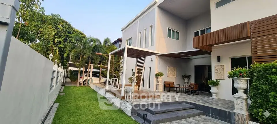 Modern two-story house with spacious patio and lush garden, perfect for outdoor living.