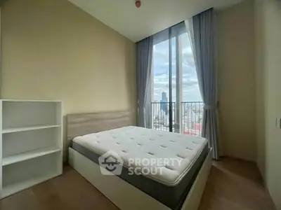 Modern bedroom with large window offering stunning city view, featuring a comfortable bed and sleek storage unit.
