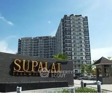 Modern high-rise condominium building with clear blue sky backdrop.