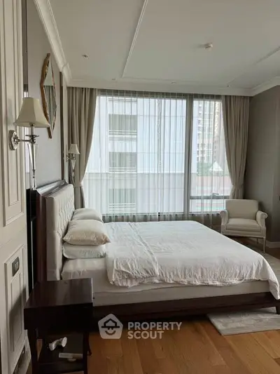 Spacious bedroom with large windows and elegant decor in a modern apartment.