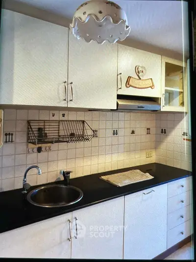 Charming kitchen with sleek black countertop and ample storage space.