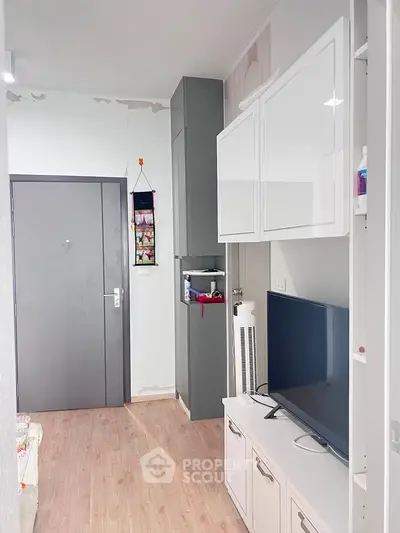 Modern living room with sleek storage and TV unit, showcasing minimalist design and efficient use of space.