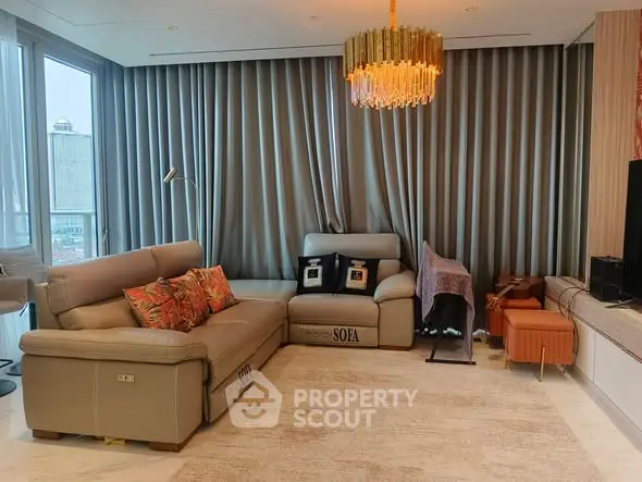Luxurious living room with elegant chandelier and modern leather sofas in a high-rise apartment.
