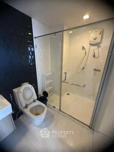 Modern bathroom with glass shower and sleek black tile accent wall