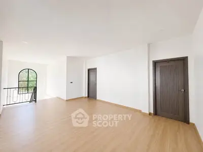 Spacious empty room with wooden flooring and large window, perfect for customization.