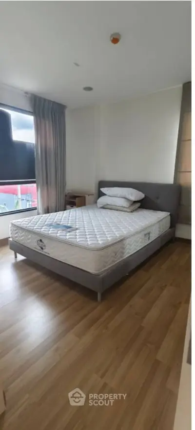 Spacious bedroom with modern design and natural light, featuring a comfortable bed and wooden flooring.