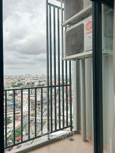 Stunning city view from a high-rise balcony with modern railing and air conditioning unit.