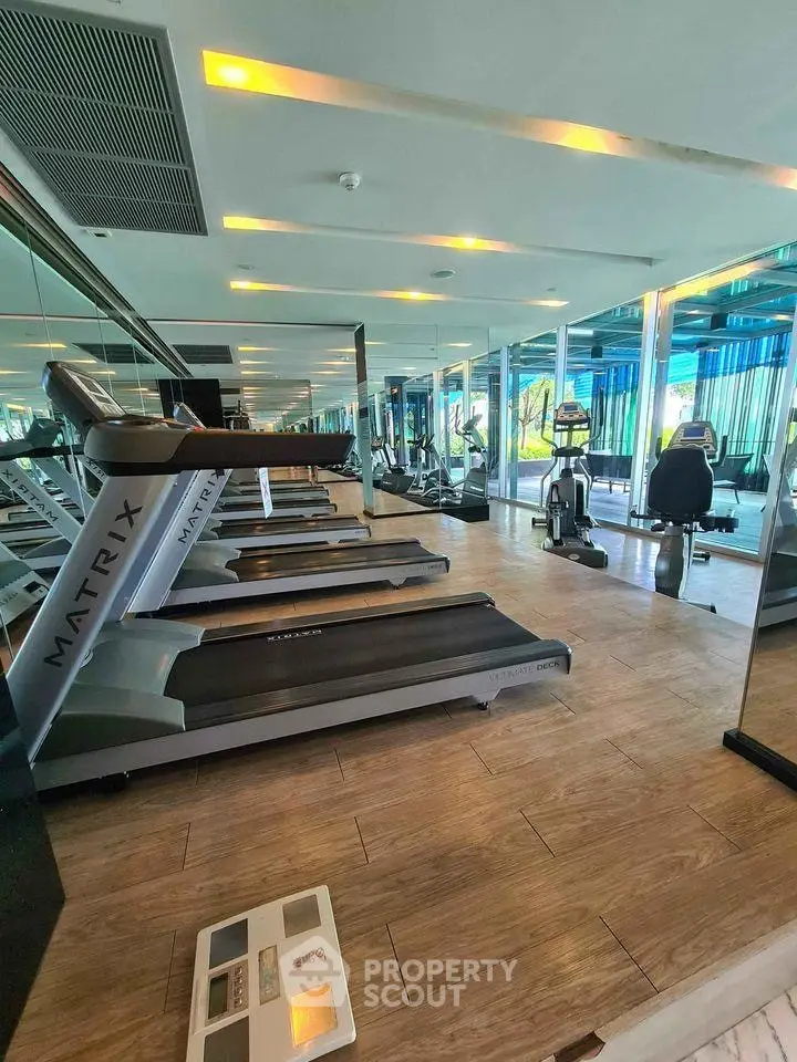 Modern gym with state-of-the-art equipment and mirrored walls in luxury residential building.