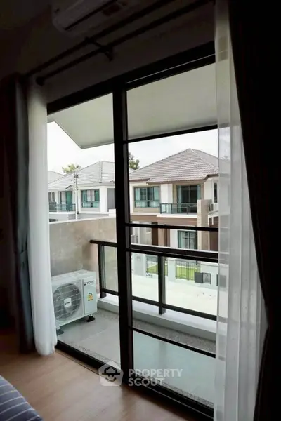 Modern balcony view with sliding glass doors overlooking residential area.