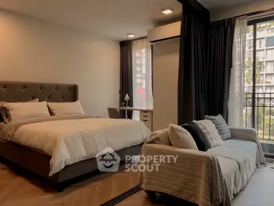 Spacious bedroom with cozy seating and balcony view in modern apartment