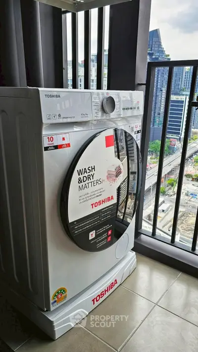 Modern Toshiba washing machine on balcony with city view, ideal for urban living convenience.