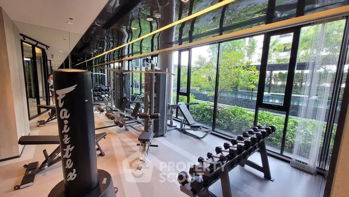 Modern gym with state-of-the-art equipment and large windows overlooking greenery.