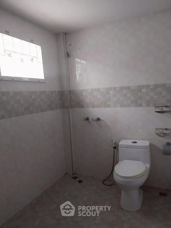 Spacious bathroom with modern toilet and tiled walls, perfect for a comfortable living experience.
