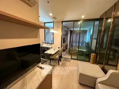 Modern open-plan living room with dining area and bedroom in a stylish apartment.