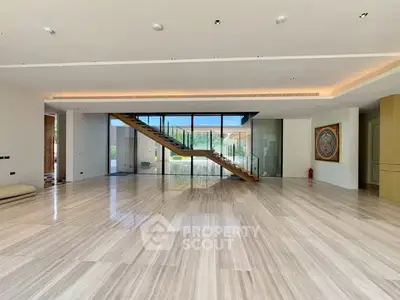 Spacious modern living room with elegant staircase and large windows