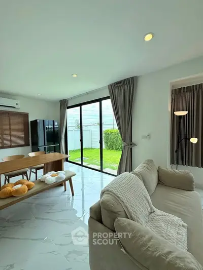 Spacious living room with modern decor and garden view, featuring cozy seating and elegant dining area.