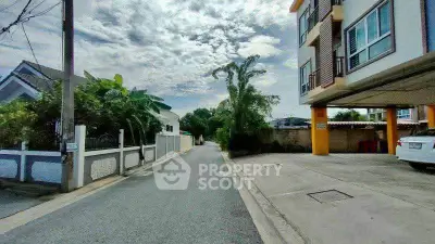 Charming residential street with modern building and lush greenery, perfect for serene living.