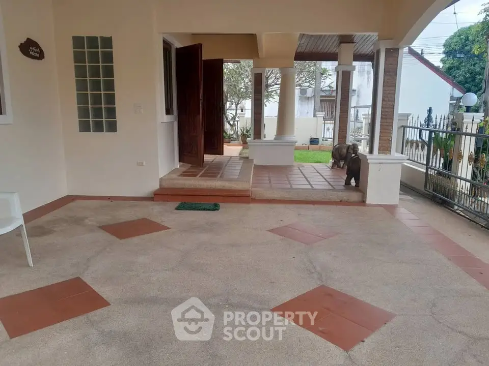 Charming entrance with spacious patio and elegant columns in a serene neighborhood setting.