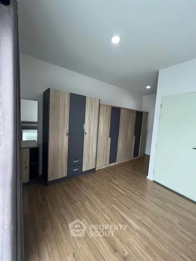Spacious bedroom with modern wardrobes and wooden flooring, perfect for stylish living.