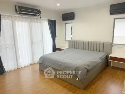 Spacious bedroom with modern decor and large windows for natural light.