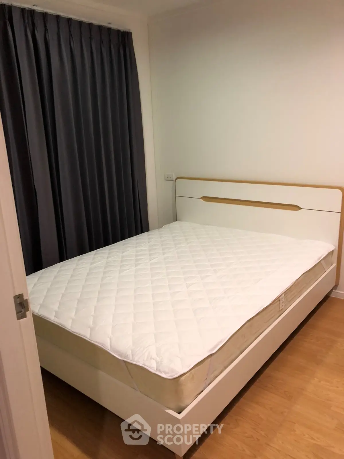 Cozy bedroom with modern bed and wooden flooring, perfect for restful nights.