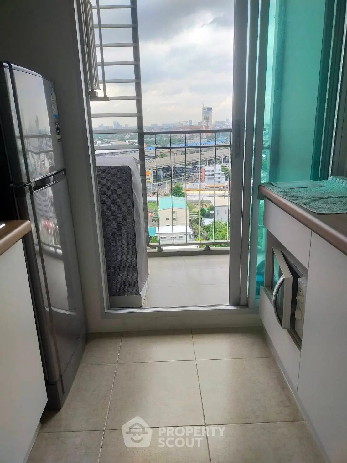 Compact kitchen with balcony view, featuring modern appliances and cityscape backdrop.