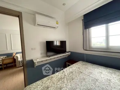 Cozy bedroom with air conditioning and TV, featuring a window view and elegant decor.