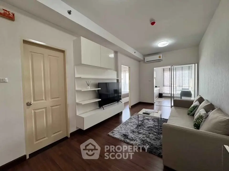 Modern living room with sleek design, featuring a cozy sofa, wall-mounted TV, and elegant decor.