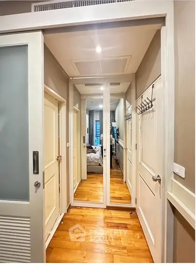 Stylish hallway with wooden flooring and mirrored closet doors in modern apartment.