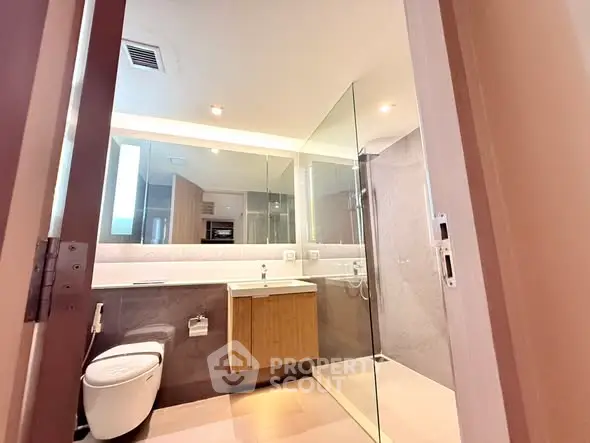 Modern bathroom with glass shower and sleek vanity in contemporary apartment.
