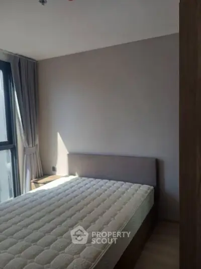 Cozy bedroom with large window and natural light, featuring a comfortable bed and modern decor.