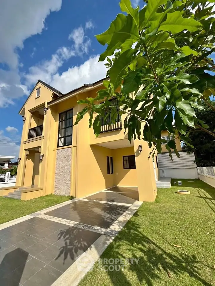 Charming two-story house with a spacious garden and elegant facade under a clear blue sky.