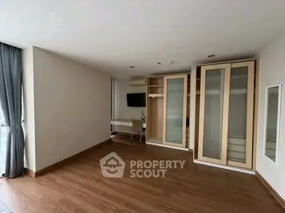 Spacious modern room with wooden flooring and built-in storage cabinets