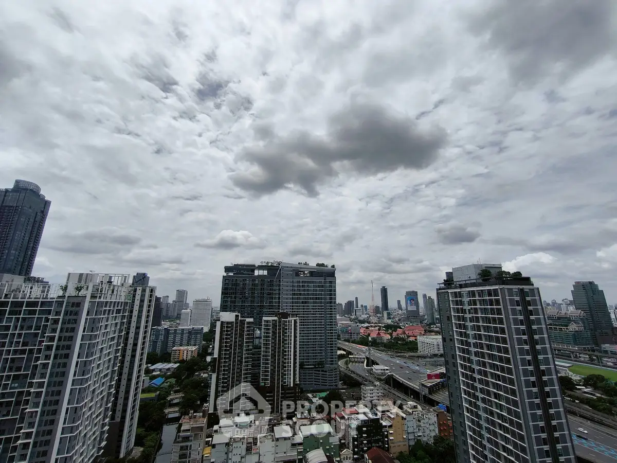 Stunning cityscape view from high-rise apartment with cloudy sky backdrop.