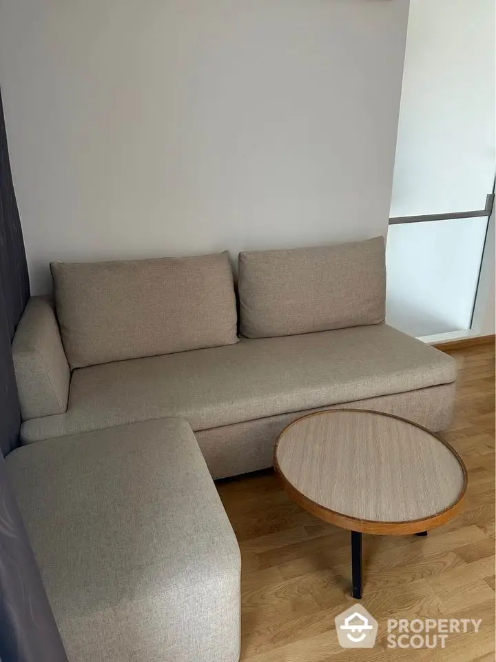 Modern living room with cozy beige sofa and wooden coffee table on hardwood floor.