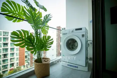 Modern balcony with washing machine and lush plant, offering urban views.