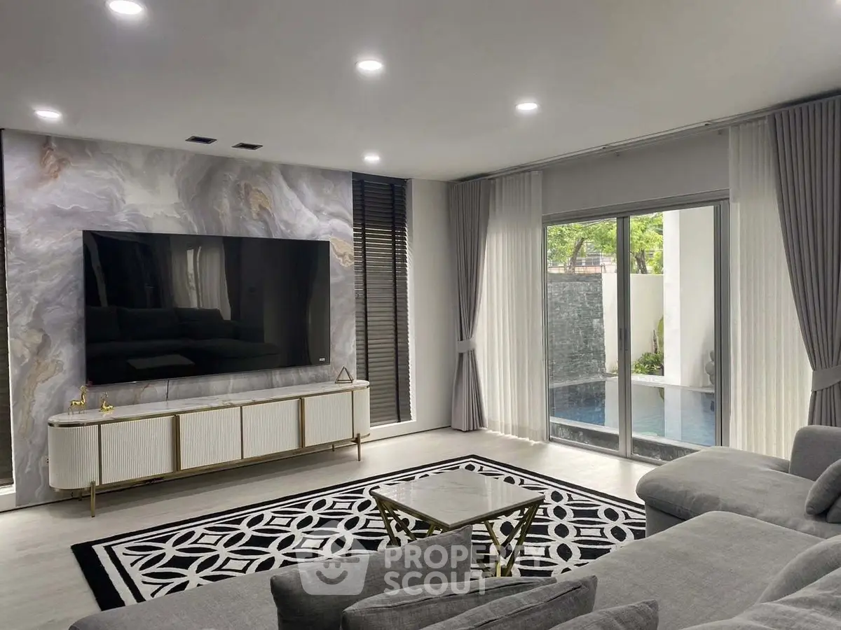 Luxurious living room with modern decor and pool view, featuring a large TV and elegant furnishings.