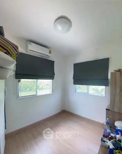 Cozy small bedroom with air conditioning and wooden flooring, perfect for minimalist living.