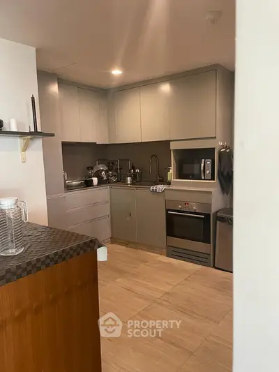 Modern kitchen with sleek cabinetry and built-in appliances in a cozy apartment.