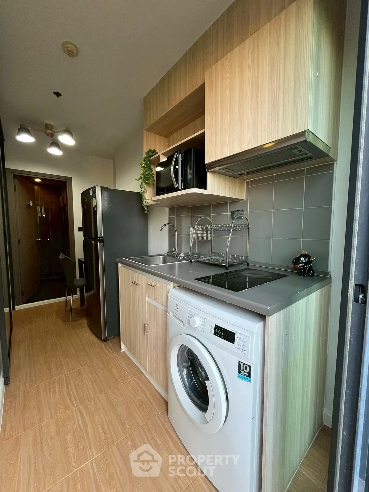 Modern kitchen with washing machine and sleek wooden cabinets in a compact layout.