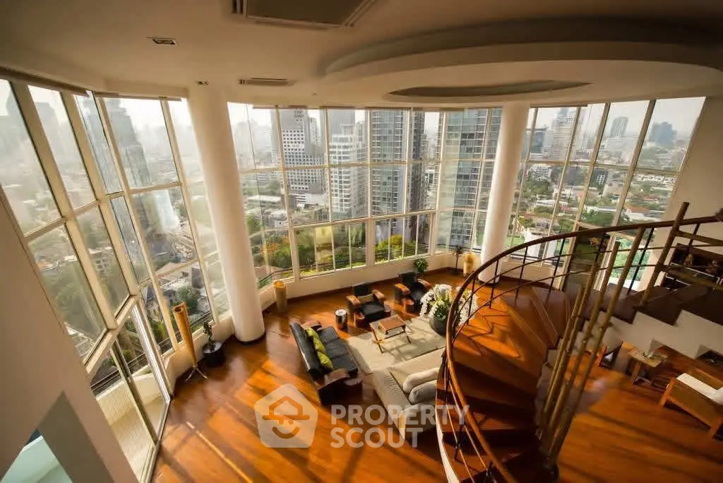 Luxurious high-rise living room with panoramic city views and elegant spiral staircase.