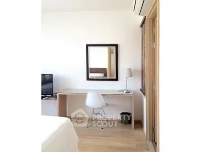 Modern bedroom with minimalist desk and chair, featuring a wall-mounted mirror and air conditioning.