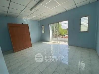 Spacious empty room with tiled floor and large windows offering natural light.