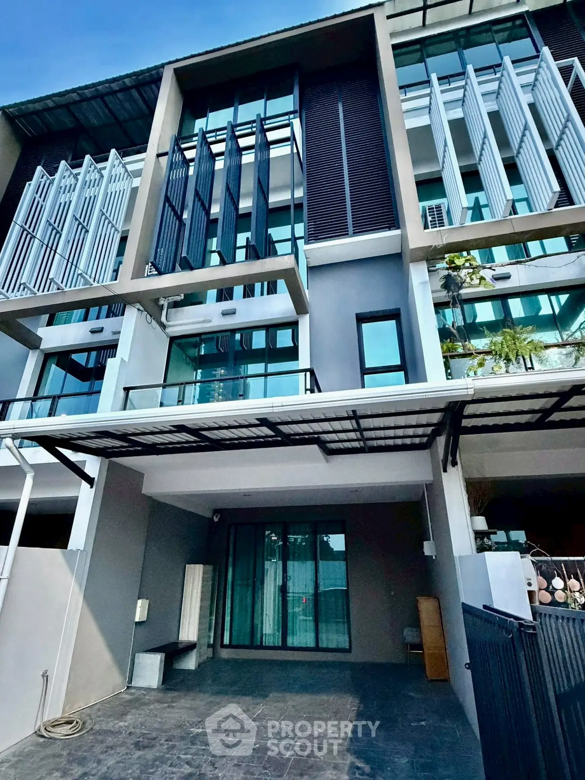 Modern multi-story townhouse with sleek facade and large windows in urban setting.