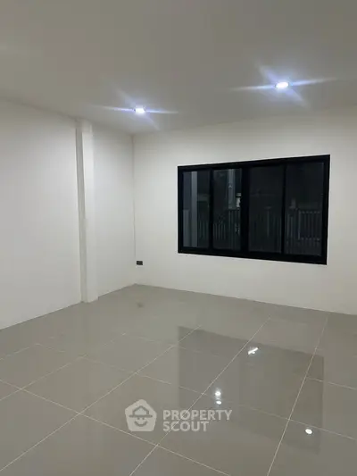 Spacious unfurnished room with modern tiled flooring and large window, perfect for customization.